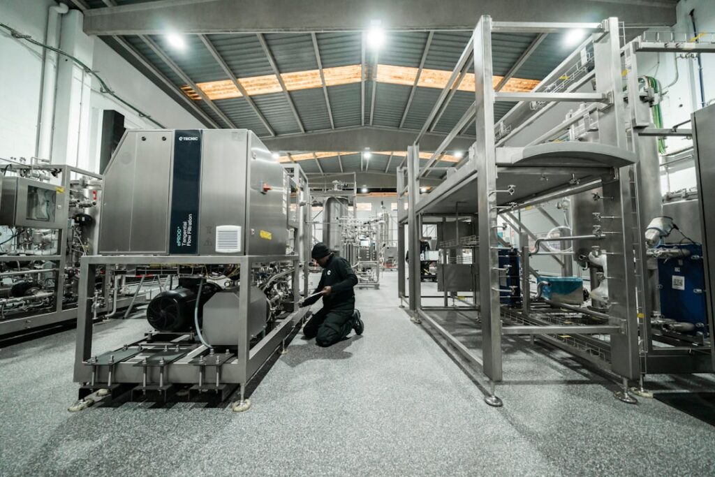 A worker repairs machinery in a factory setting.