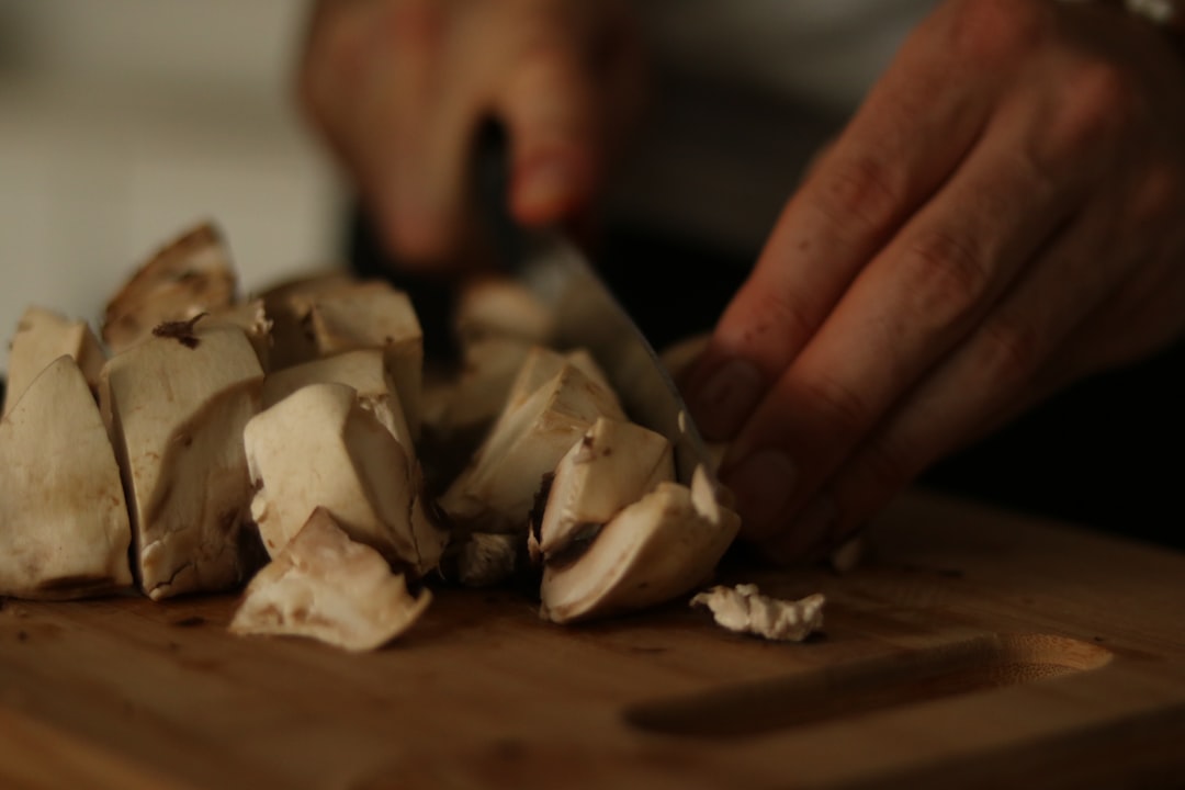 a person chopping mushrooms on a cutting board