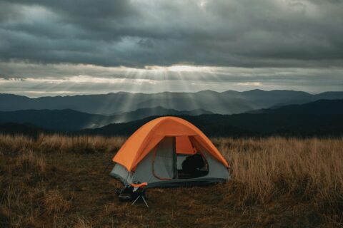 set-up gray and orange tent on brown field under cloudy sky