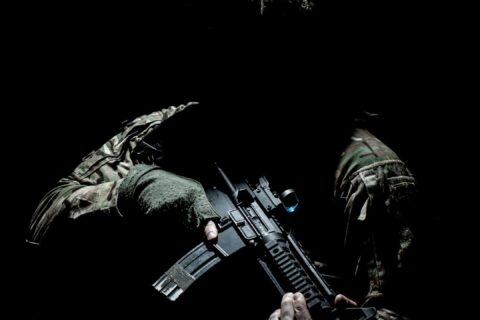man in black and green camouflage suit holding rifle