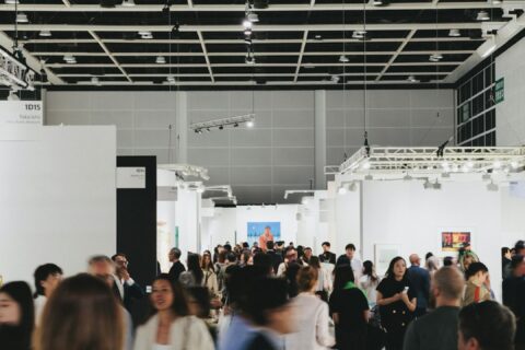 People browse art in a busy, modern gallery.