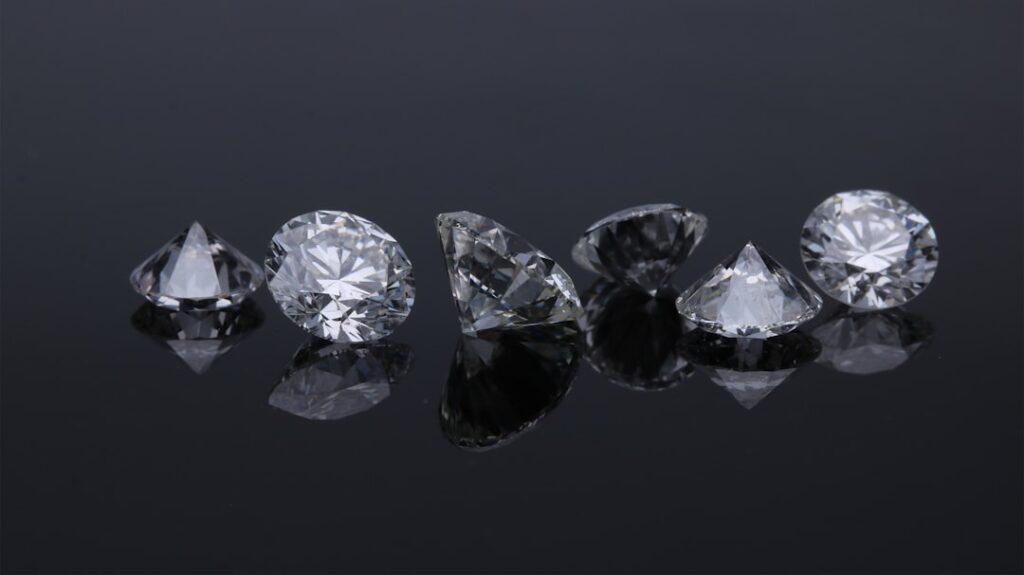 Six faceted diamonds arranged in a row on a reflective black surface