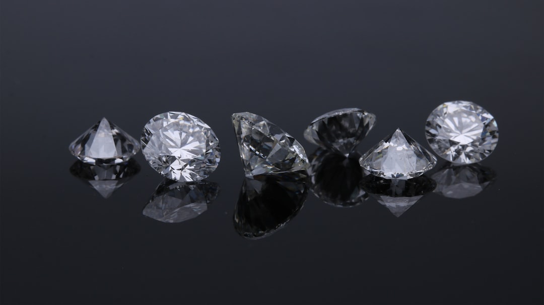 Six faceted diamonds arranged in a row on a reflective black surface