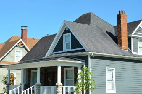 A blue house with a white porch and red chimney